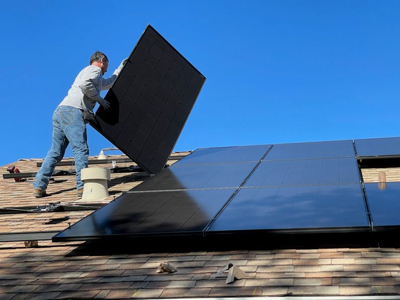 Solar Panels - man in white dress shirt and blue denim jeans sitting on white and black solar panel