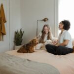 Pet-friendly Flooring - woman in white long sleeve shirt sitting on bed beside brown dog